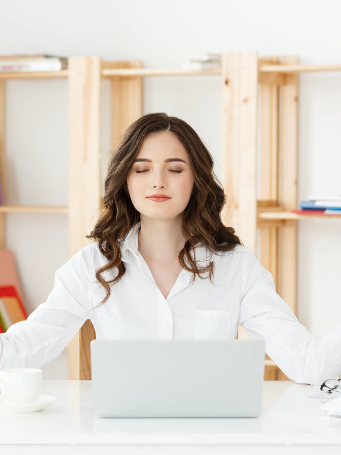 Sky Yoga shala Business and Health Concept: Portrait young woman near the laptop, practicing meditation at the office desk, in front of laptop, online yoga classes, taking a break time for a minute.