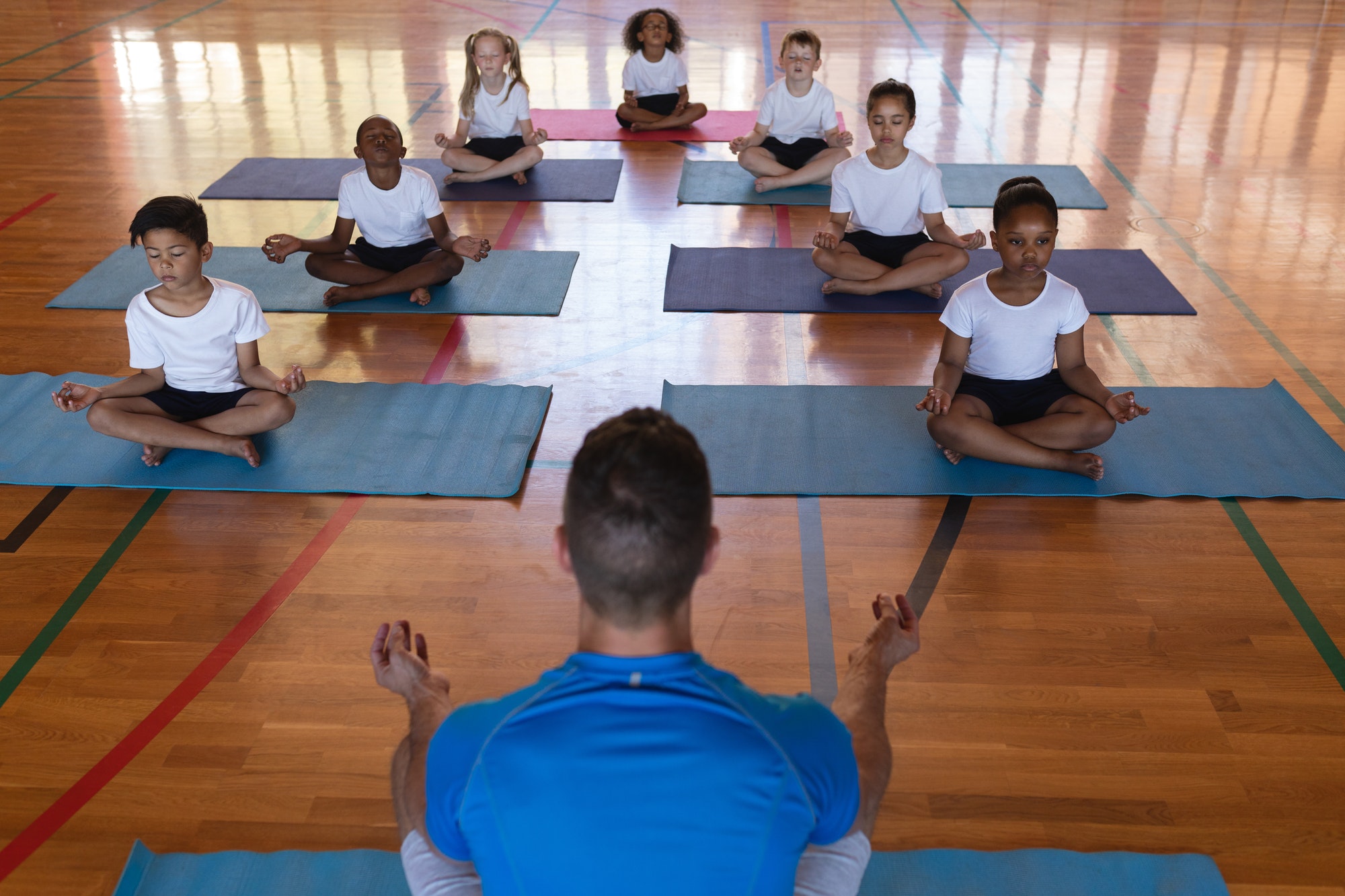 Yoga teacher teaching yoga to school kids in school